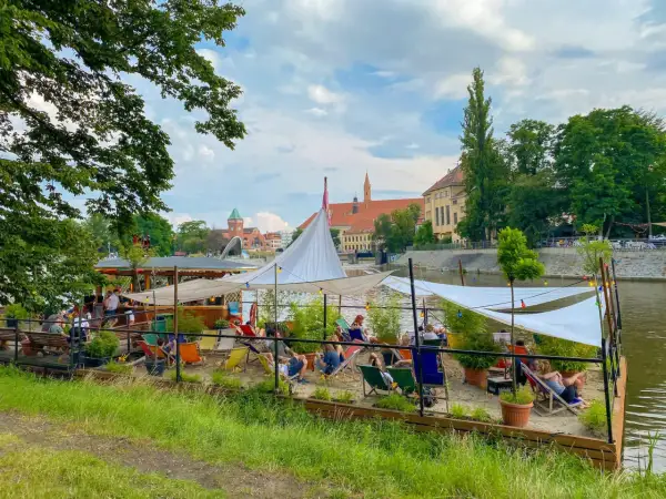 Entspannte Atmosphäre an einem Flussufer-Café in Breslau. Ein perfekter Ort für Breslau Geheimtipps, mit Liegestühlen und Sonnensegeln.