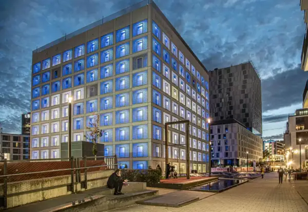 Die Stadtbibliothek Stuttgart leuchtet in der Dämmerung mit blauen Fenstern.